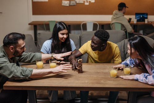 Free Friends engaging in a fun board game in a cozy indoor setting with drinks. Stock Photo
