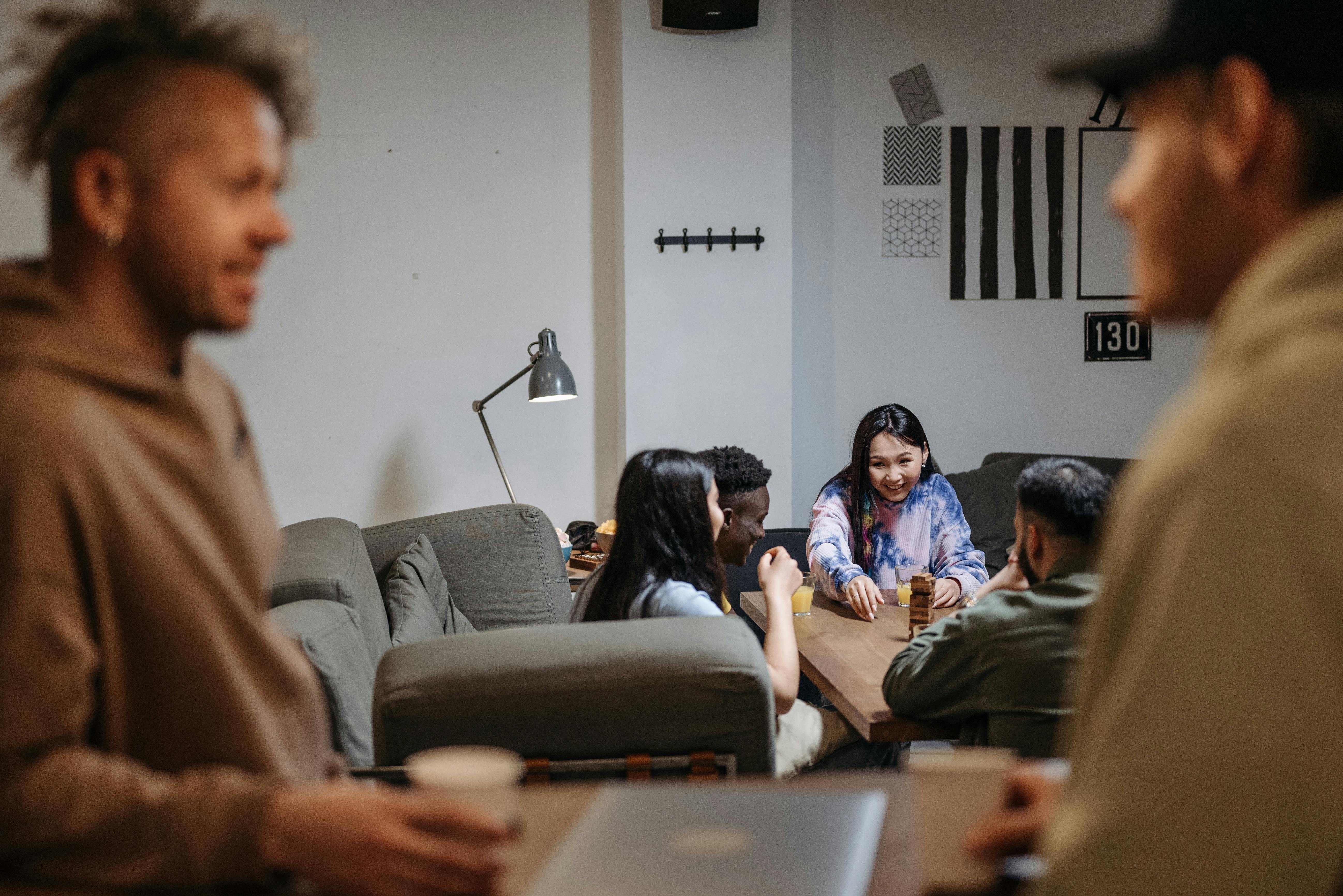 a small group of people sitting in a circle in a cozy living room, talking and laughing