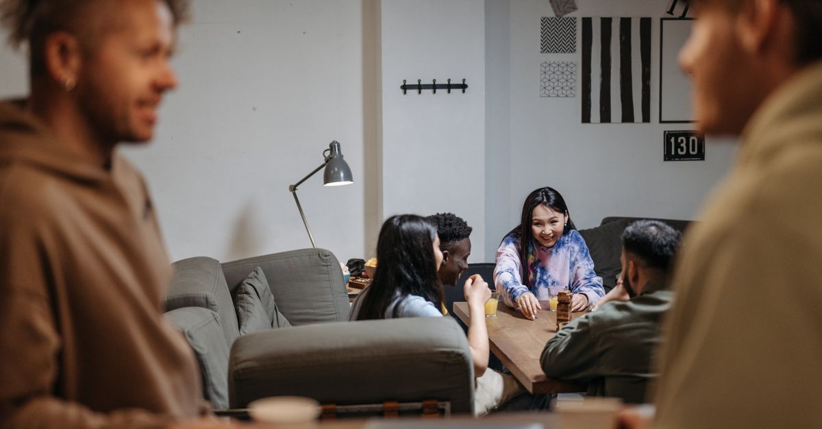 a small group of people sitting in a circle in a cozy living room, talking and laughing