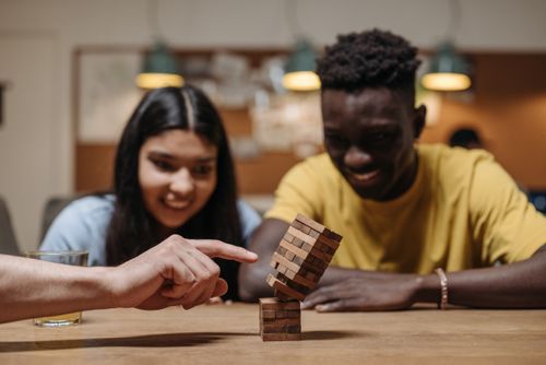 Free Smiling young adults playing a wooden block game indoors, enjoying fun and laughter. Stock Photo