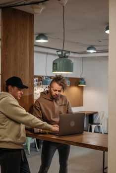 Two men in a modern workspace collaborating on a laptop, showcasing teamwork and focus.