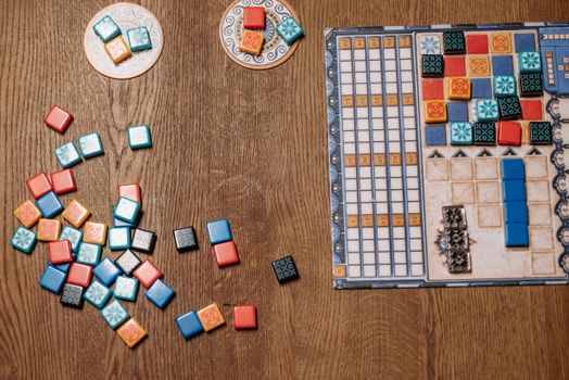 Top view of a strategy board game with colorful tiles and game board on a wooden table.