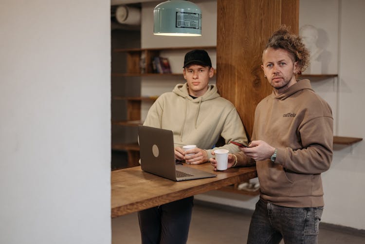 Men In Hoodies By Table With Laptop At Office