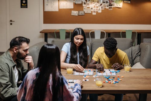 Free People Sitting on a Wooden Table Playing Board Game Stock Photo