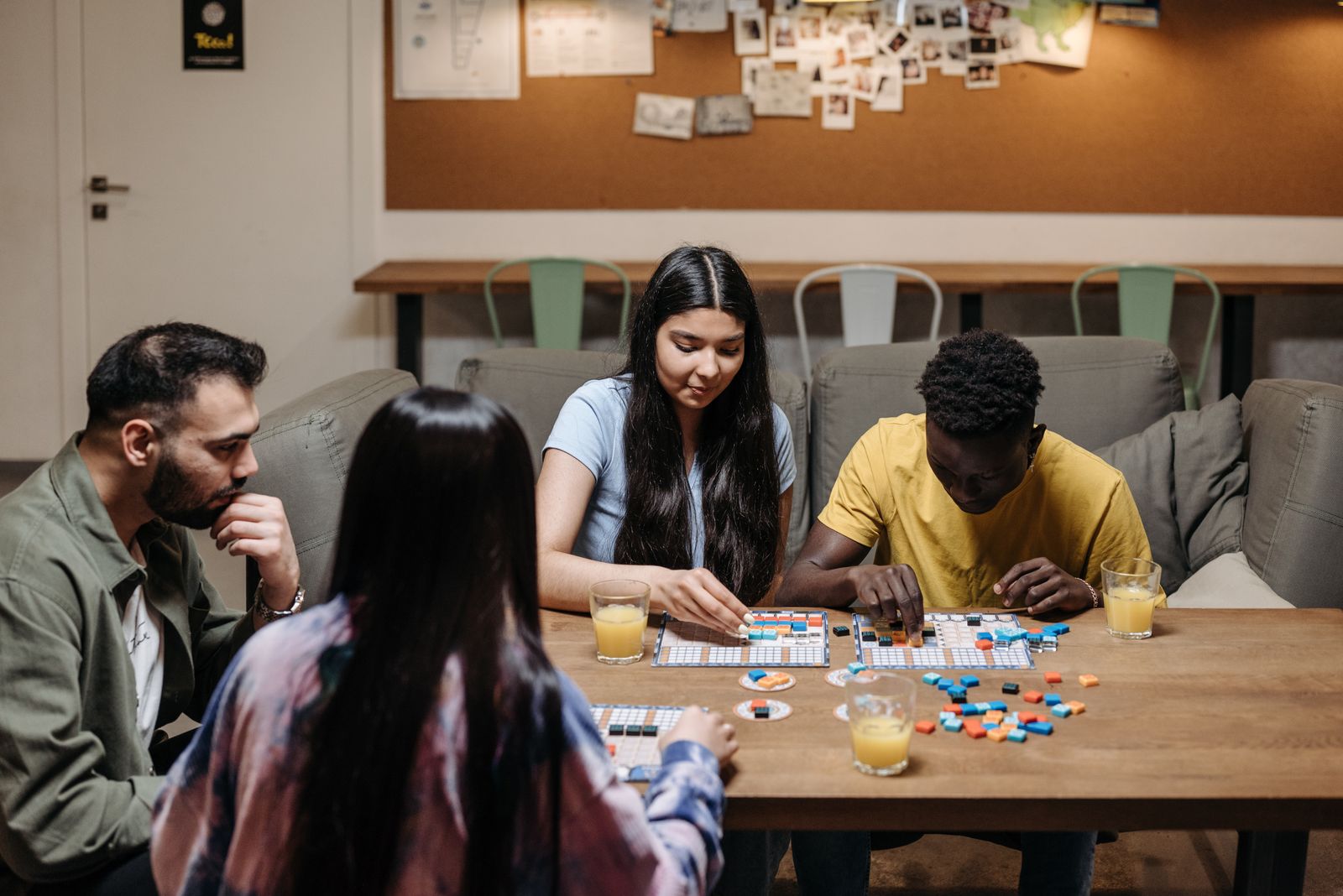 Four people playing a board game together around a table