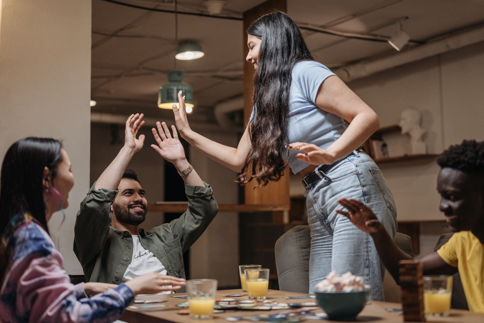 A diverse group of friends having fun playing board games indoors, exhibiting joyful expressions.