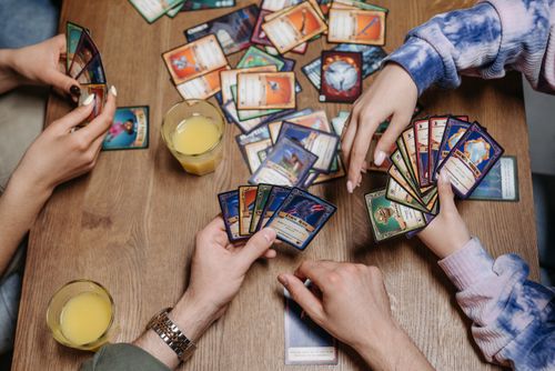 Free Close-up of friends playing a card game at a table, fostering socialization and togetherness. Stock Photo