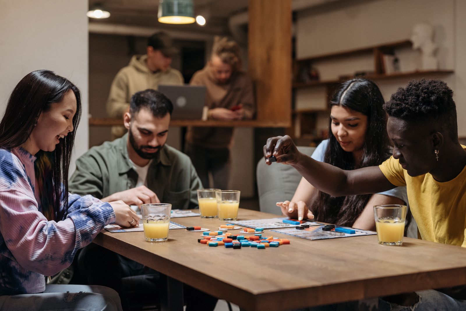 A small group of adults playing a tabletop board game together at a table