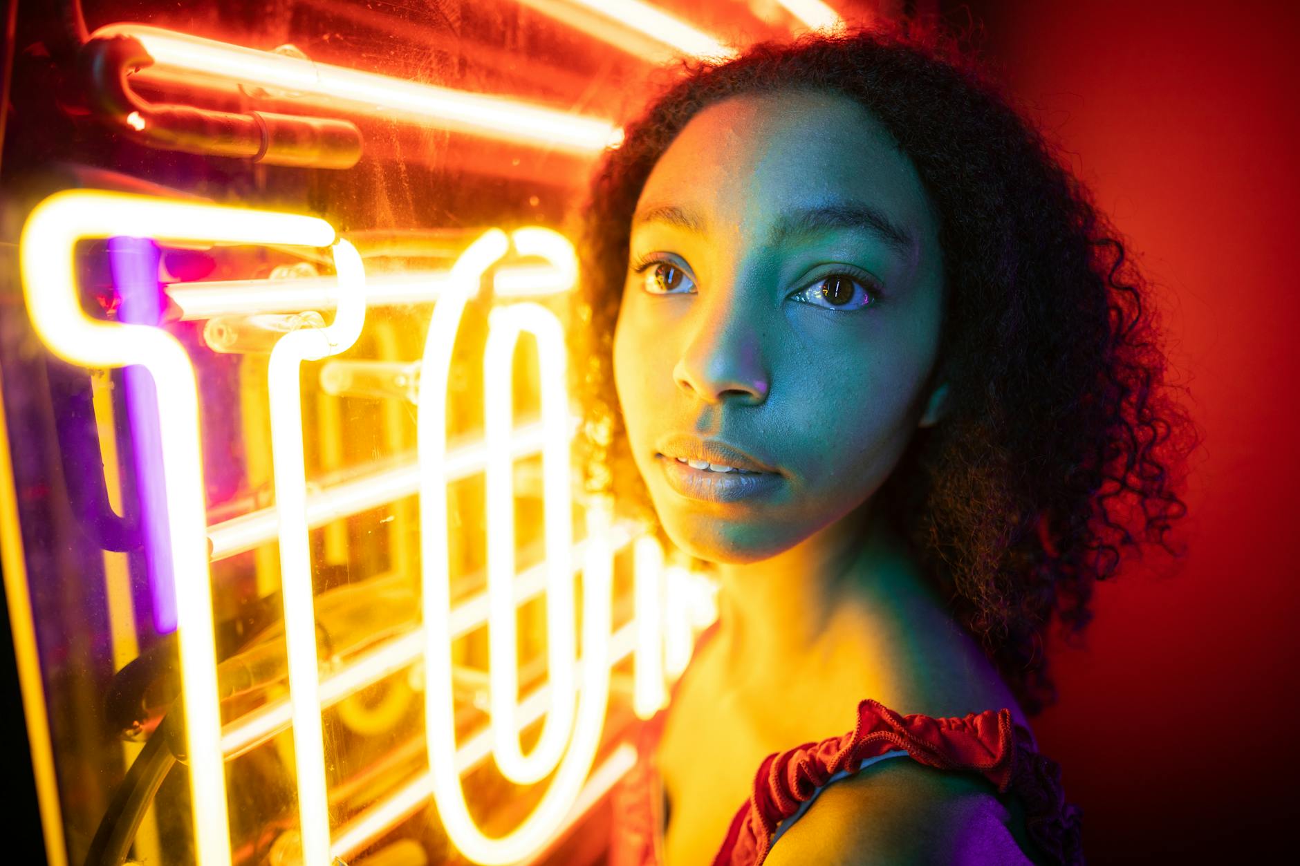 A captivating portrait of a young woman illuminated by vibrant neon lights.