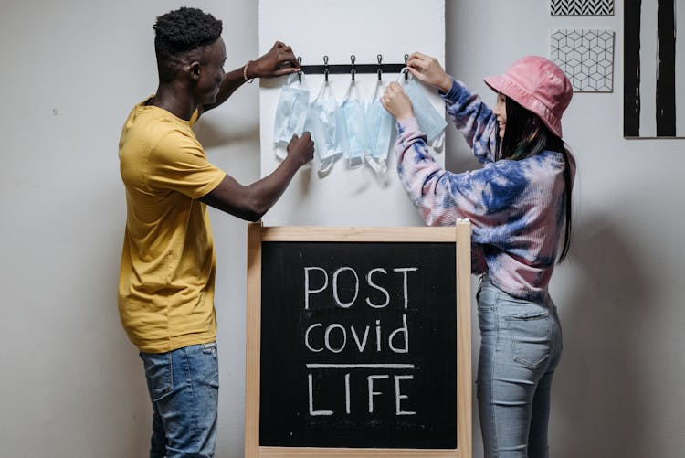 Woman And Man Putting Masks On Hooks On Wall