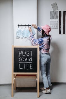A woman places masks on hooks in a post-COVID life theme indoors.