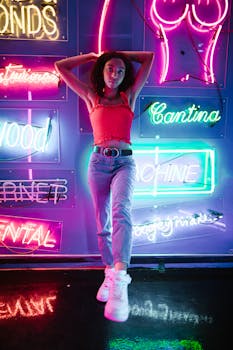 Young woman posing against vibrant neon backdrop, showcasing modern street fashion style.