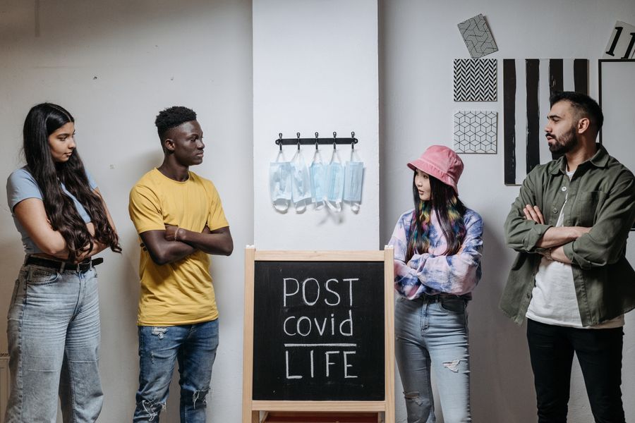 A group of diverse adults discussing life after COVID-19 indoors, highlighting socialization and safety.
