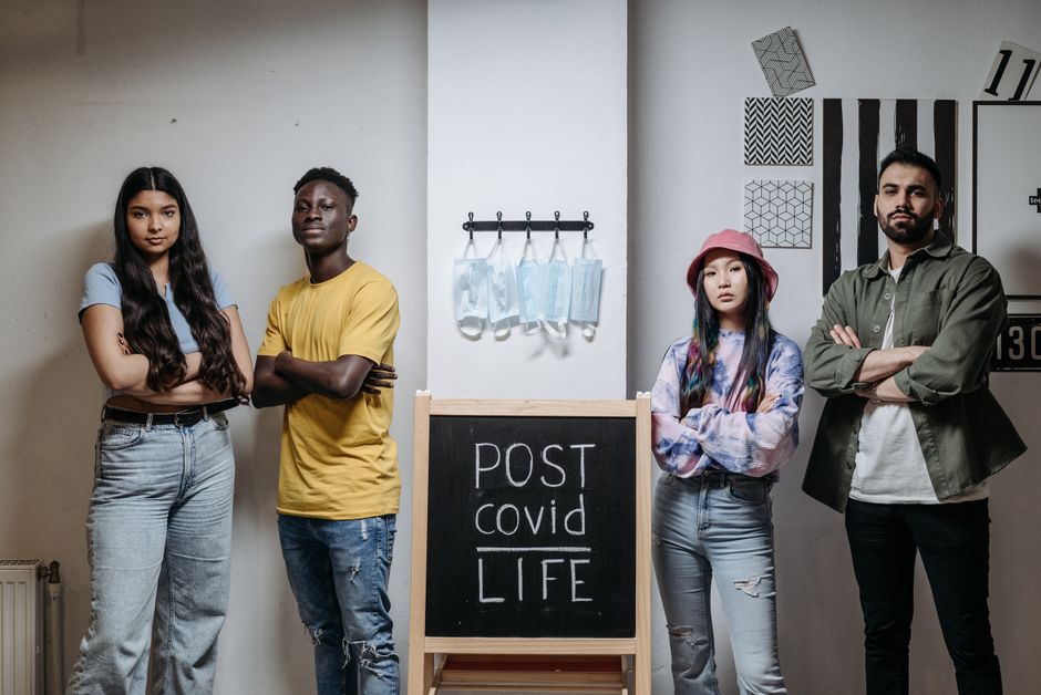 future of work skills in a post-pandemic world - A diverse group of young adults poses beside a chalkboard reading 'Post COVID Life'.