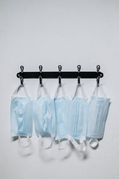 Five face masks hanging neatly on black hooks, still life photo.