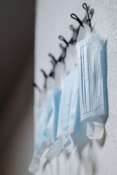 Close-up view of blue medical masks hanging on hooks, symbolizing health protection.