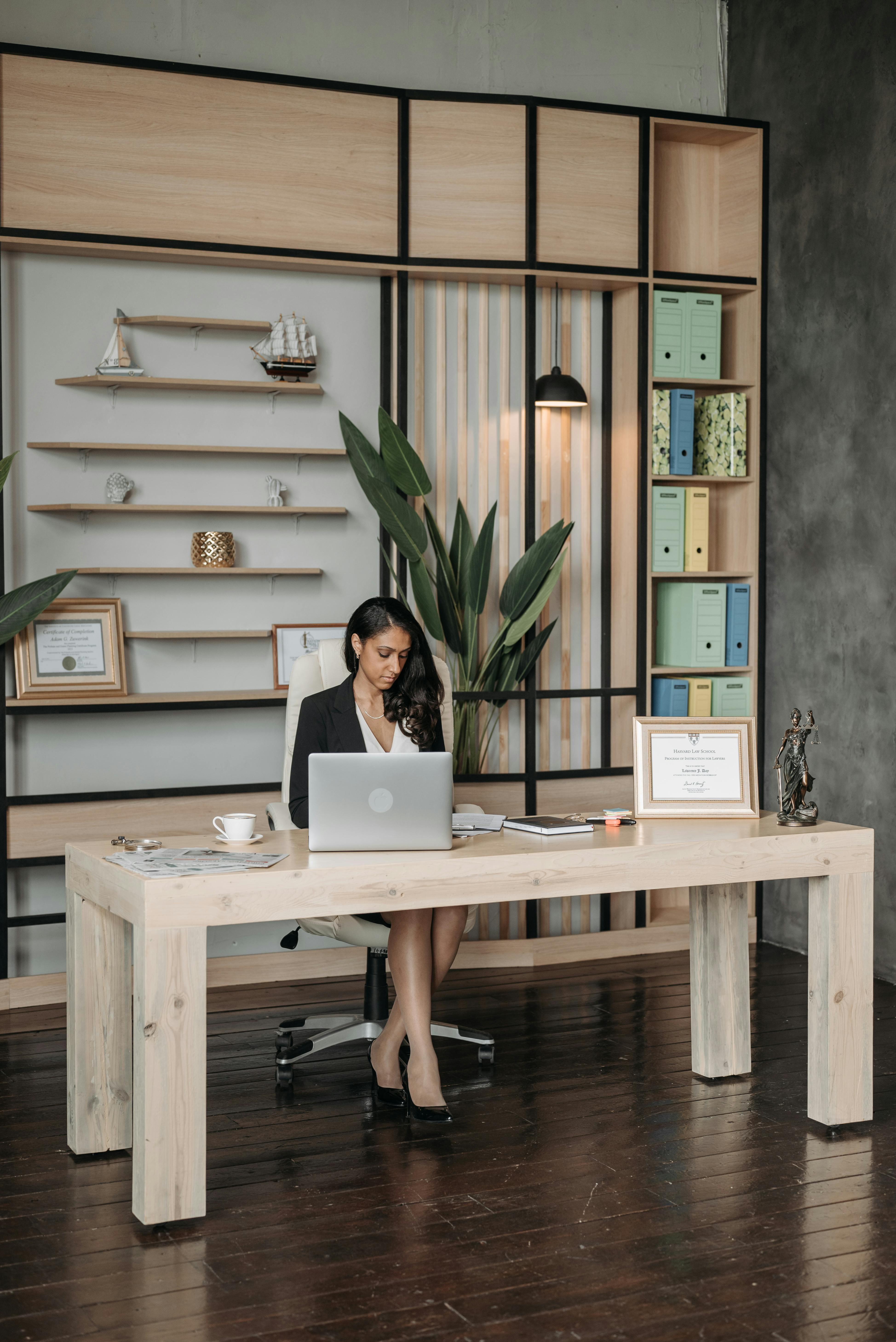 a woman in black blazer working while sitting near the wooden table