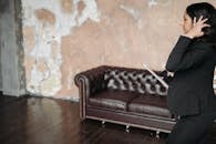 Person in Black Pants Sitting on Brown Couch