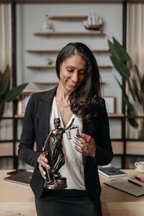 Portrait of Smiling Woman Standing with Justice Figurine