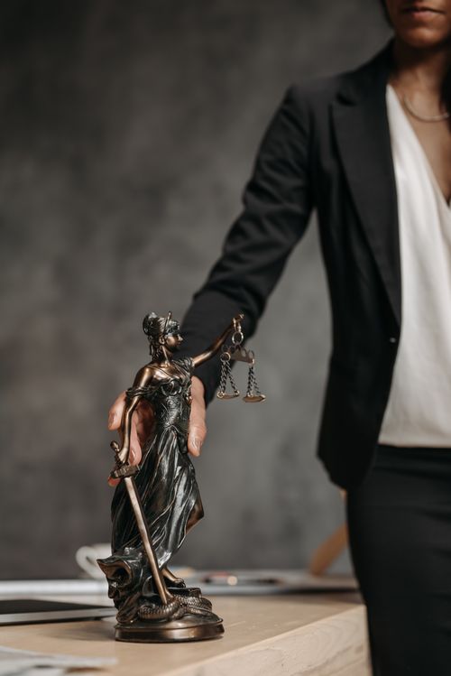 Free A professional woman holds a bronze Lady Justice figurine on a desk, symbolizing legal justice. Stock Photo