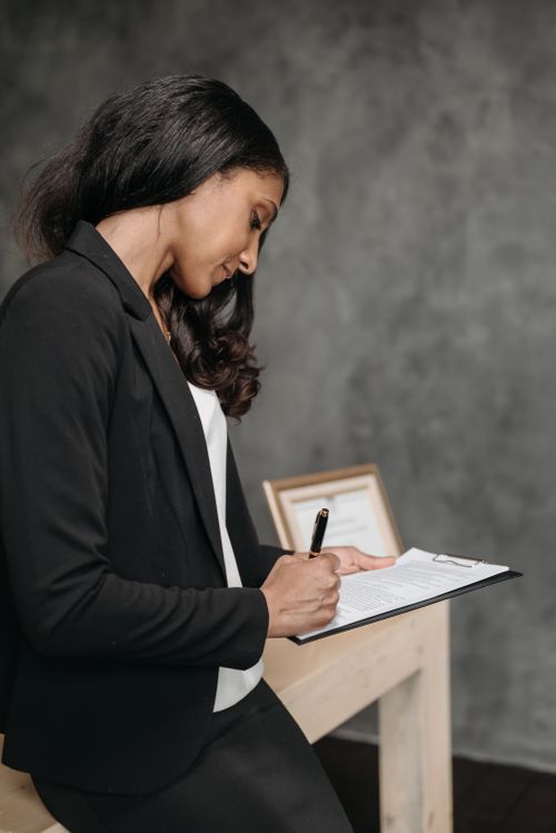Free Side profile of a businesswoman writing notes in a modern office setting. Stock Photo