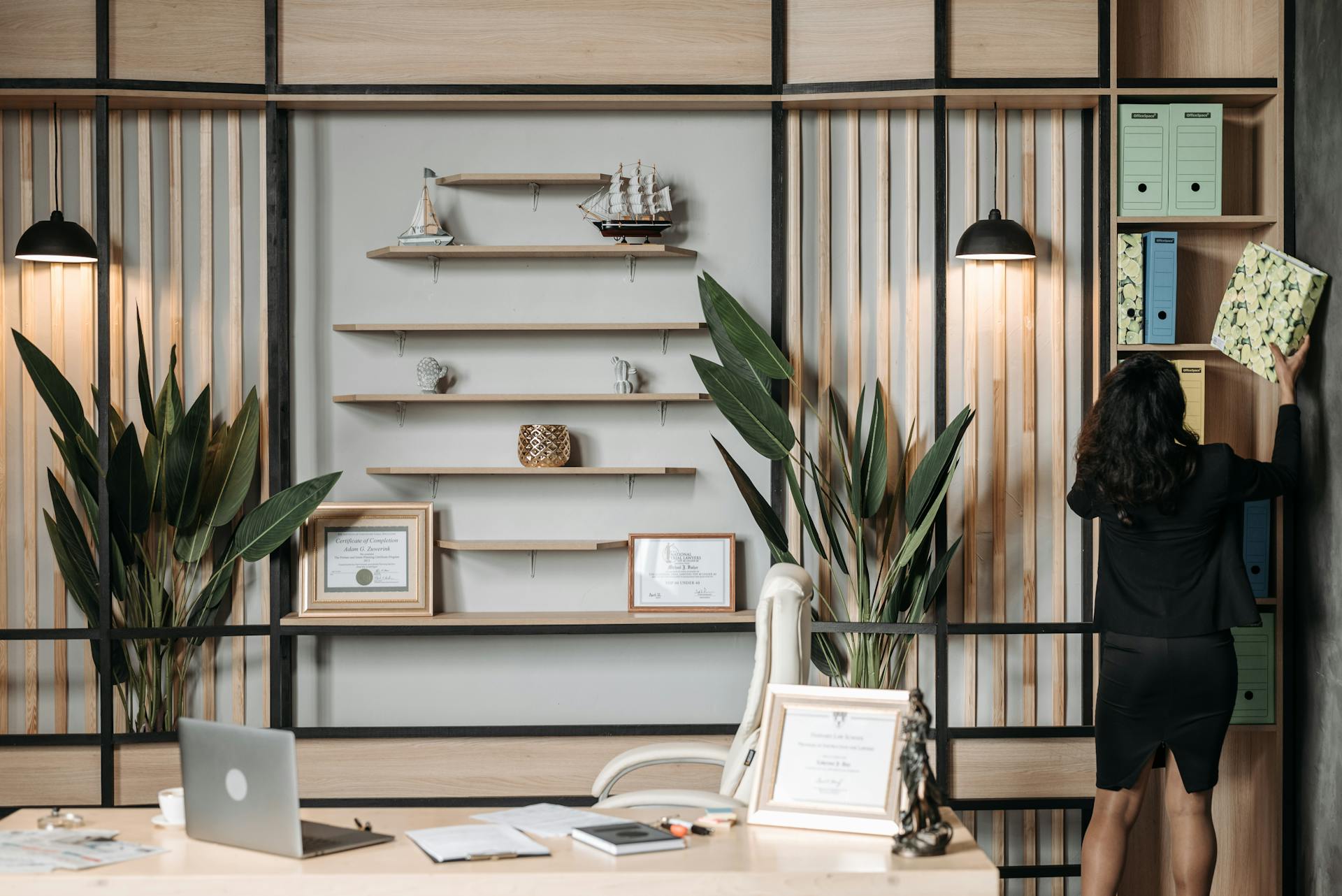 Elegant office interior with a businesswoman organizing files on a shelf.