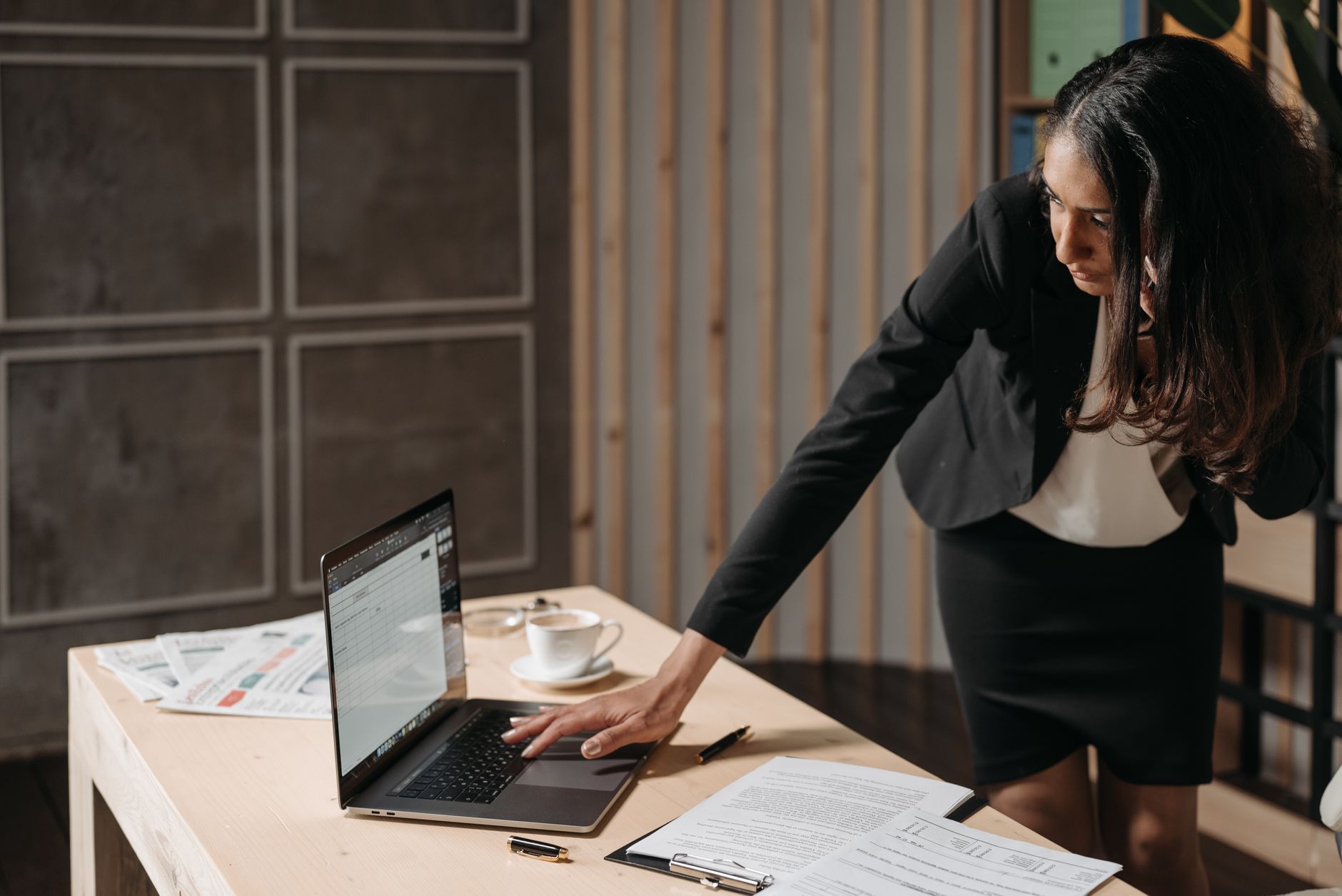 Professional businesswoman multitasking at an office desk, focused on her tasks with a laptop. (Photo by Pavel Danilyuk on Pexels)