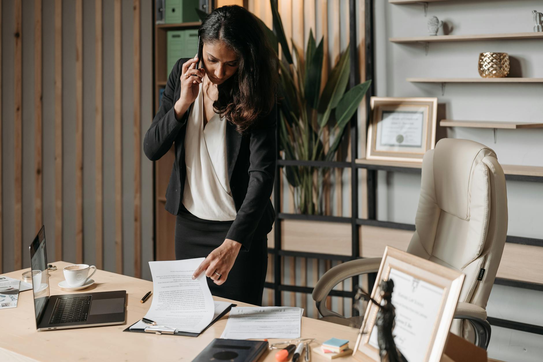 A female lawyer talking on phone while reviewing legal documents in a modern office setting