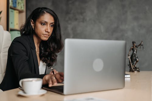 Woman in Suit Sitting and Working on Laptop