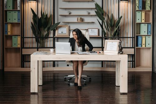 Free Businesswoman in a stylish office working on a laptop, surrounded by office supplies. Stock Photo