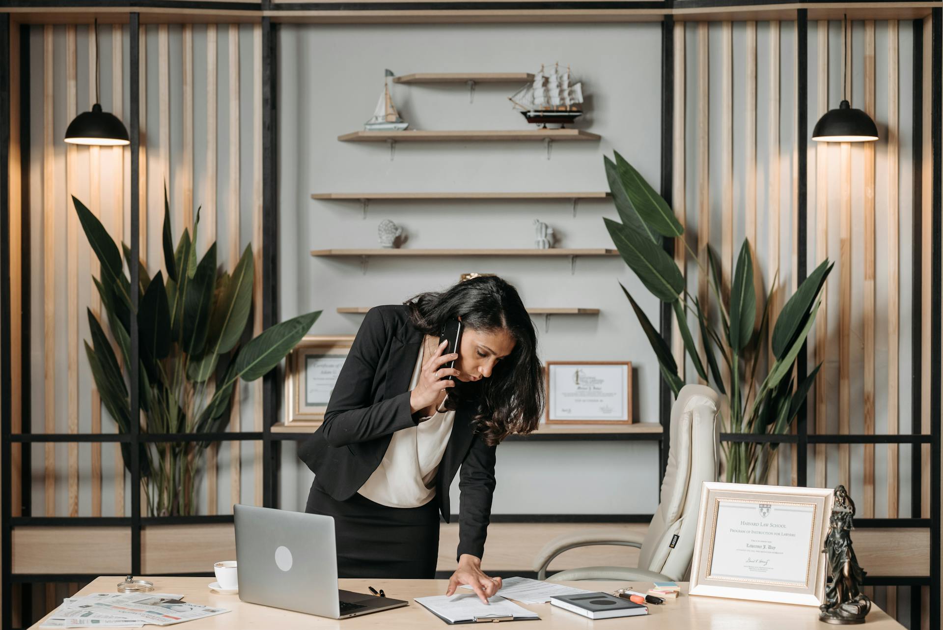 A professional woman lawyer multitasking in a modern office environment, reviewing documents.