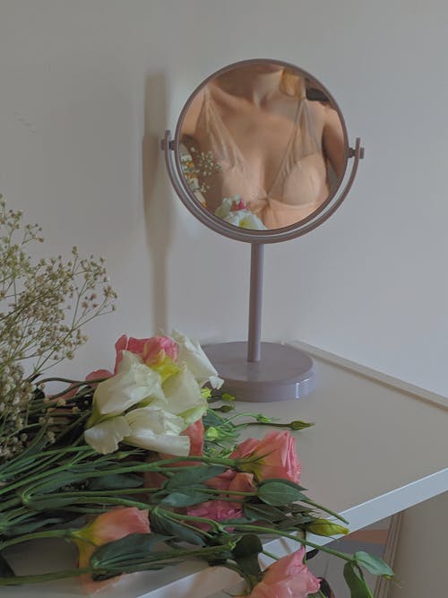 A Blooming Flowers on the Table Near the Mirror