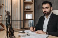 Man in Black Suit Jacket Writing on White Paper