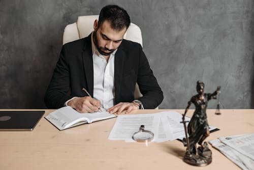 Free A Man in Black Suit Writing on Notebook Stock Photo