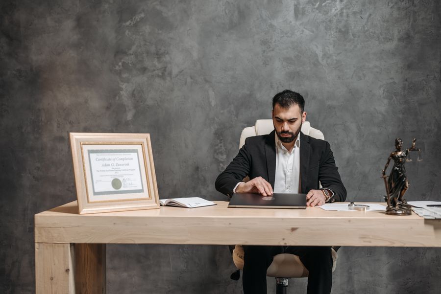 Bearded professional lawyer R. Surendran Pillai, Partner, in a business suit working on a laptop at his office desk