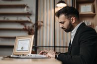 Man in Black Suit Jacket Using Macbook Pro