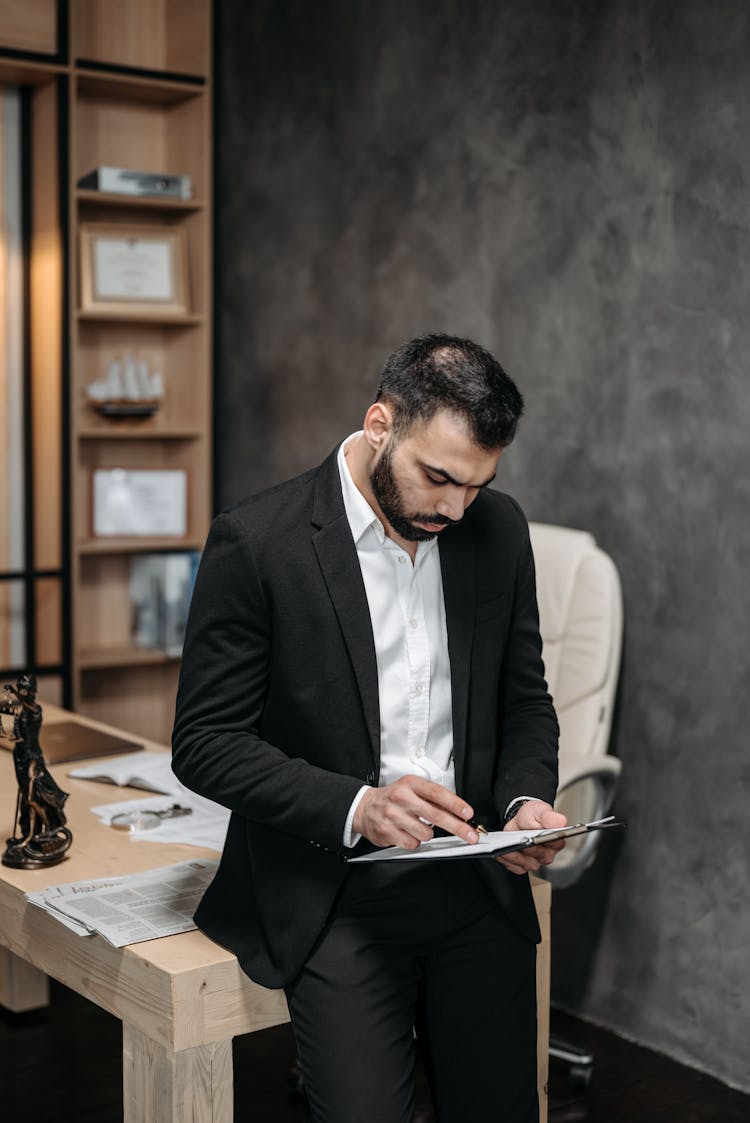 A Man In Black Suit Reading A Contract