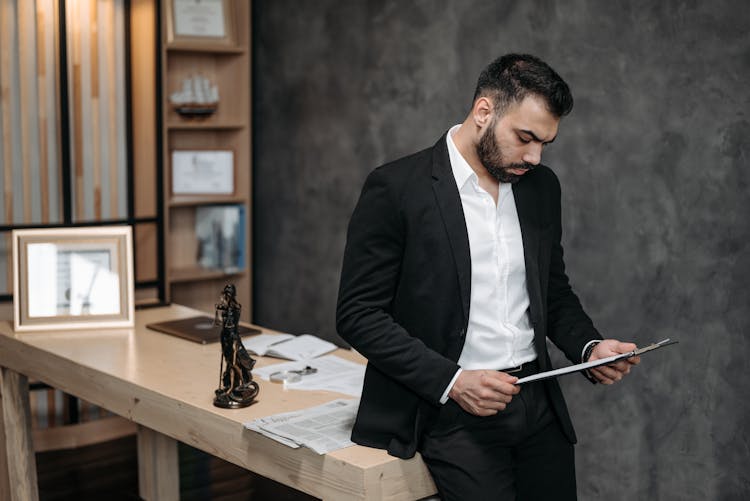 A Man In Black Suit Reading A Contract