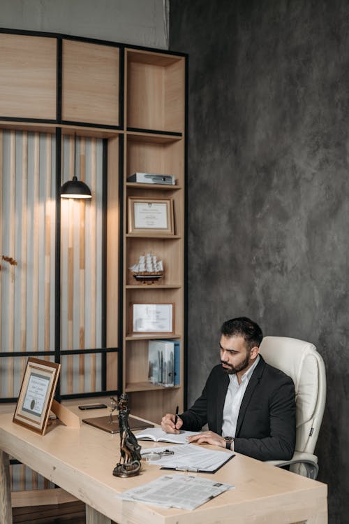 Man in Black Suit Sitting by Desk and Working