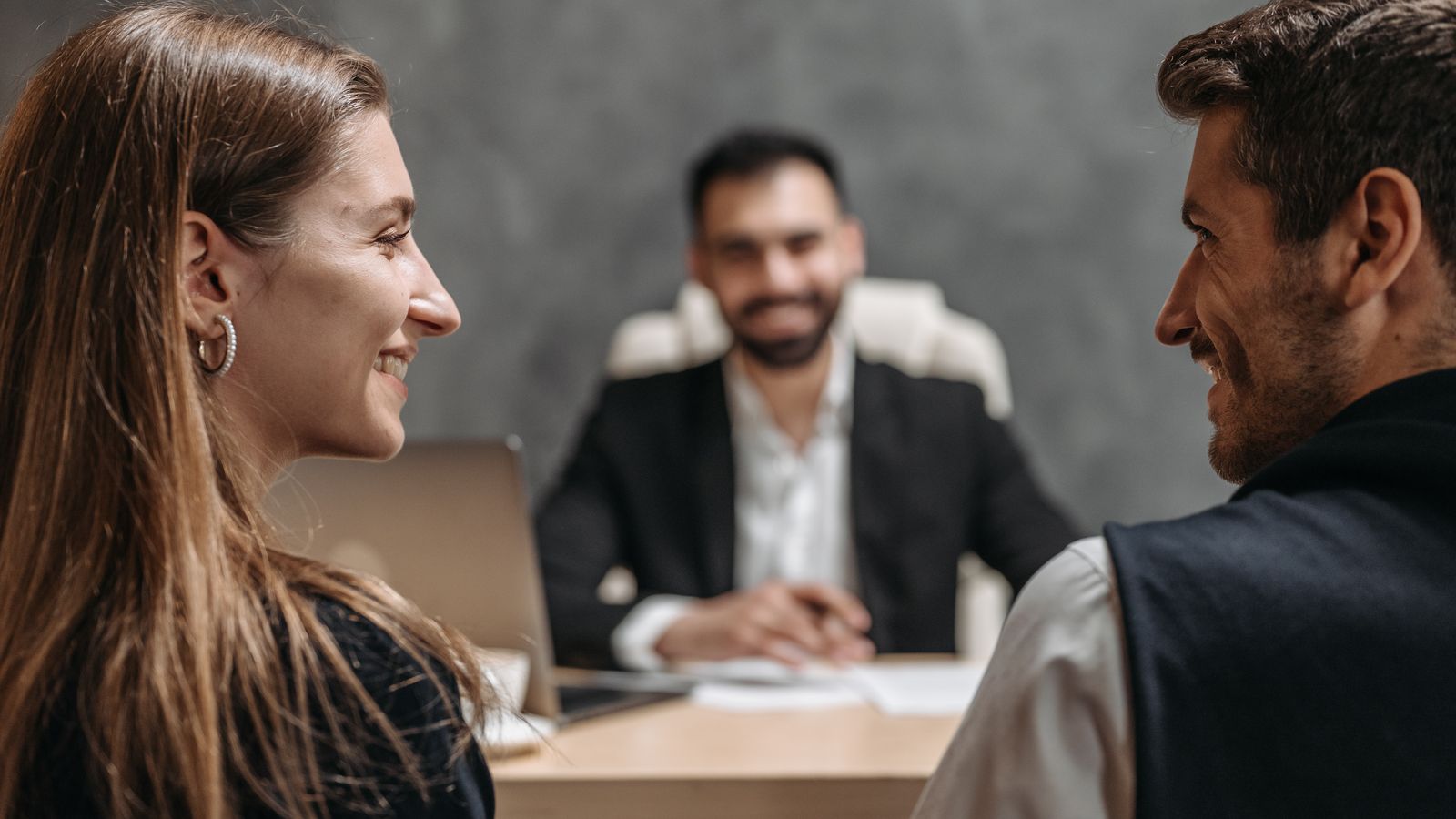 A couple meeting an adviser across a desk in an office.
