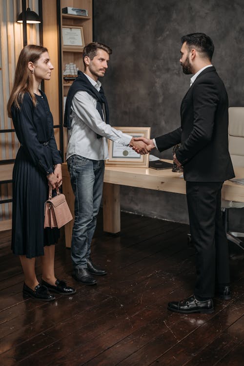 Man in Black Suit Shaking Hands with Man in White Long Sleeve Shirt