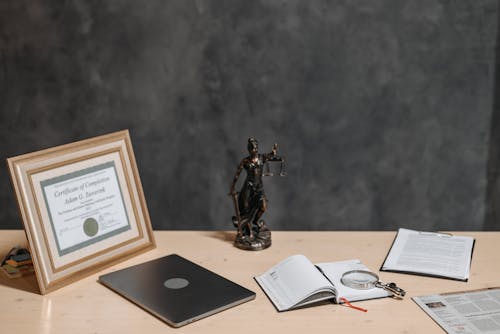 Diploma Figurine and Documents on a Desk 