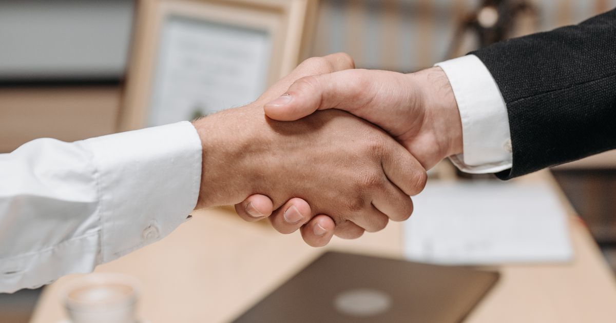 Zwei Personen geben sich im Büro die Hand als Sinnbild für die geregelte Übergabe eines Reinigungsbetriebs