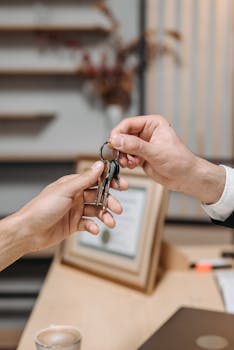 A real estate agent handing over house keys, symbolizing property ownership transfer.