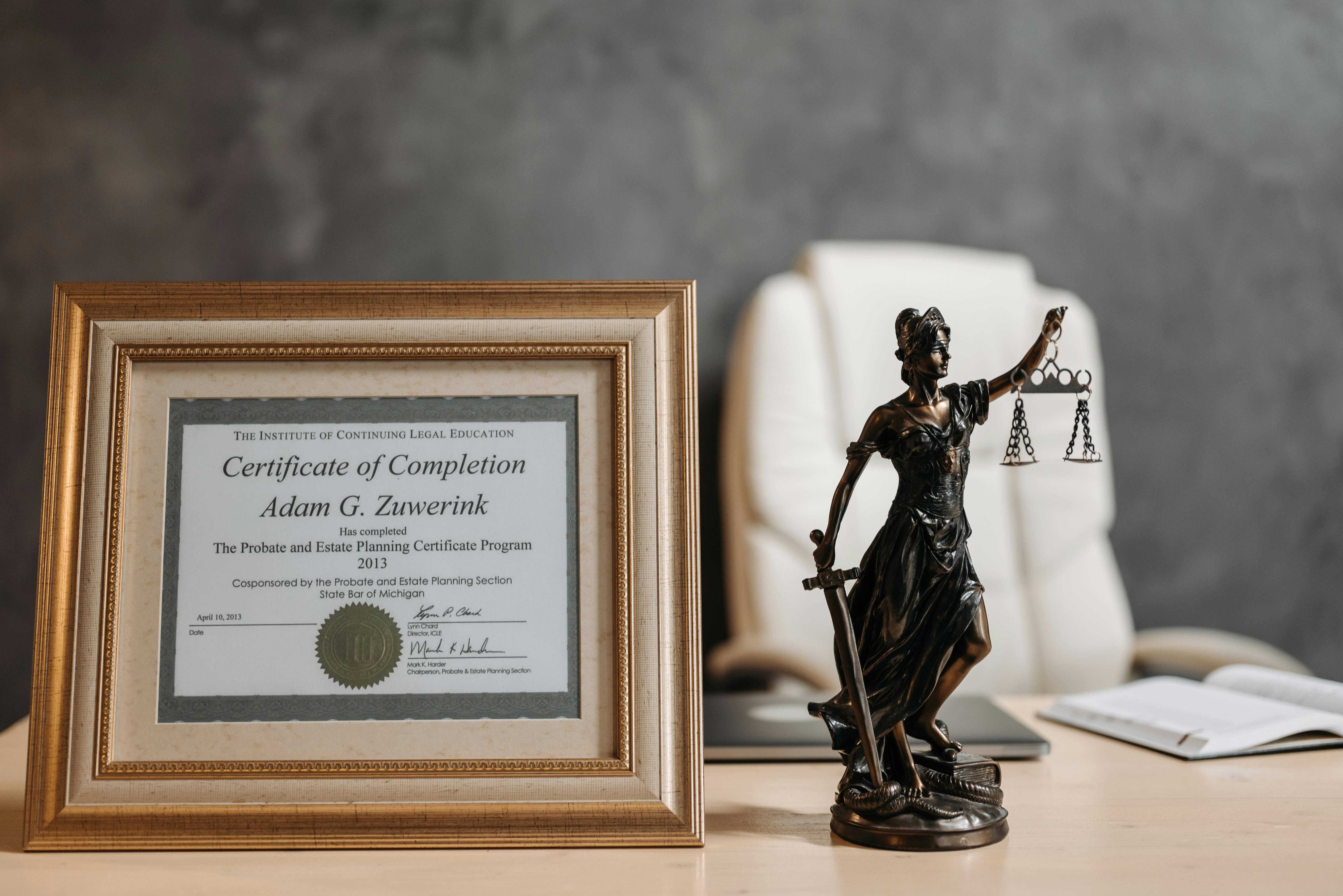 a certificate and lady justice figurine on table