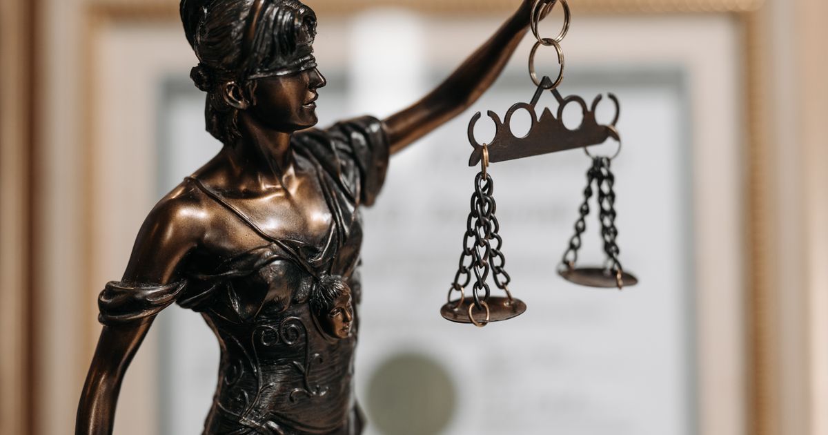 Close-up of a bronze Lady Justice statue holding scales in an office environment.