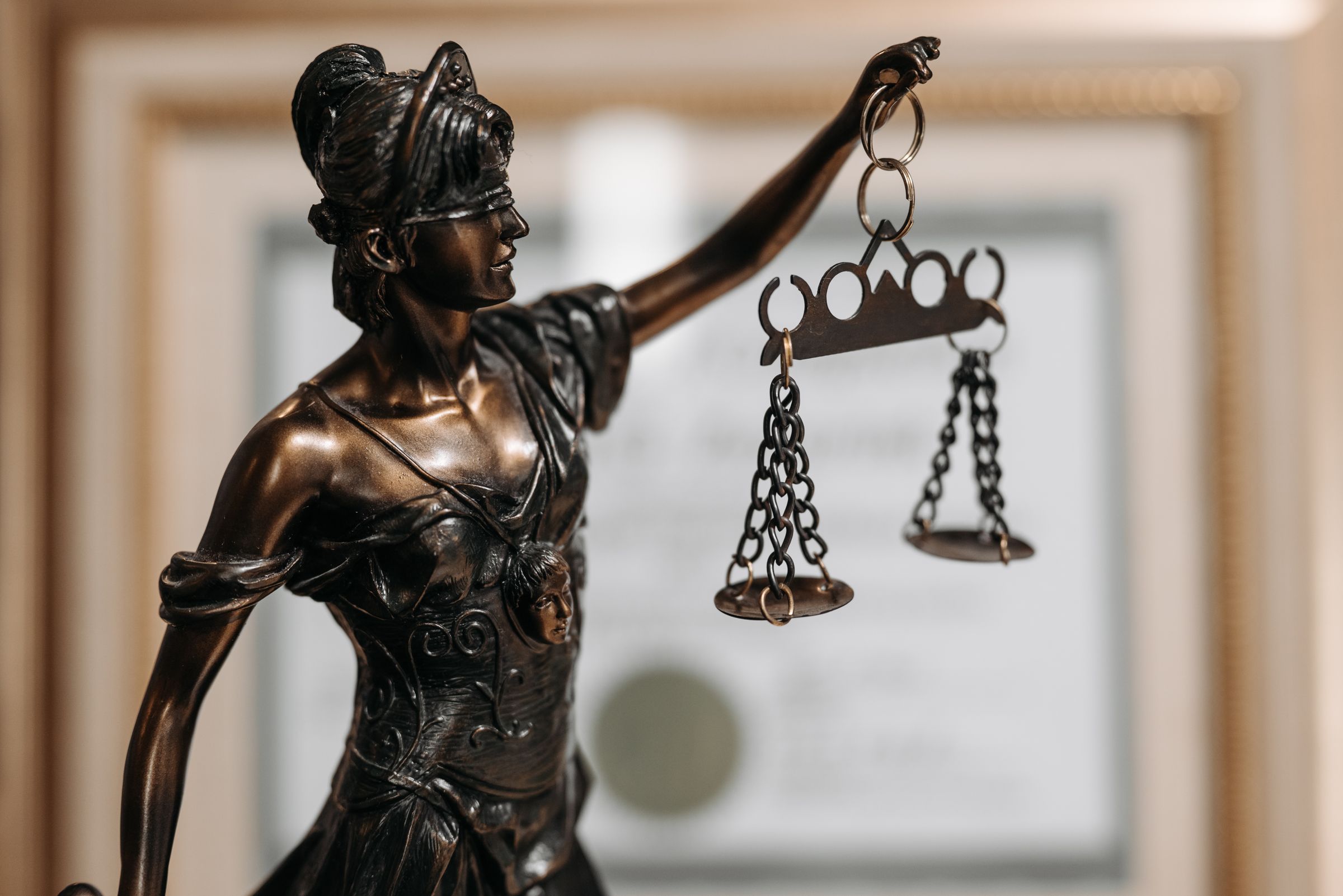 A bronze statue of the scales of justice in front of a framed certificate