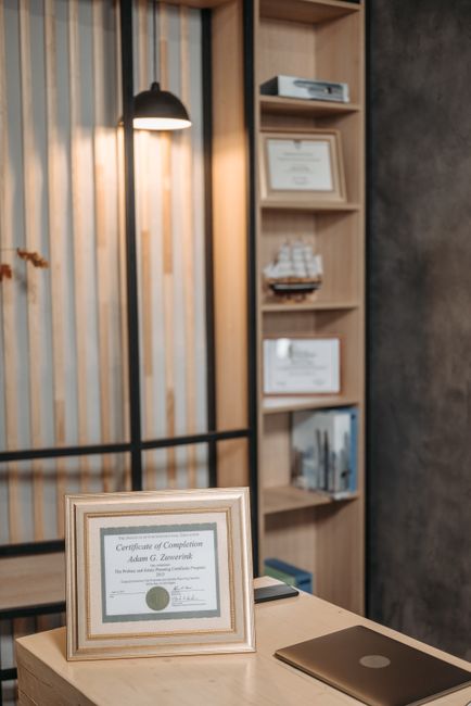 Stylish office interior featuring a framed diploma, modern desk, and elegant lighting.
