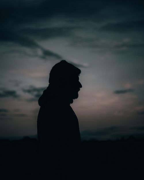 Free A dramatic silhouette of a man against a cloudy twilight sky, capturing the tranquil mood. Stock Photo