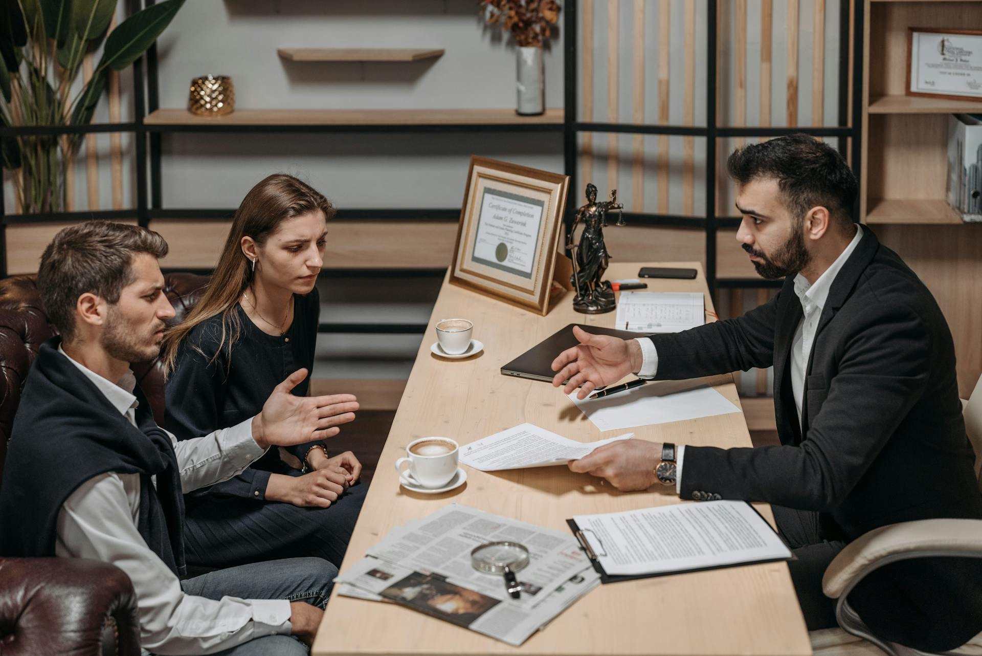 Lawyer consulting clients in an office. Documents and coffee on the table.